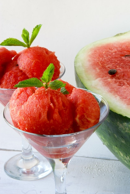 Wassermelone mit einem Löffel zum Schneiden von Cocktailbällchen, ein Glas mit Wassermelonenkugeln