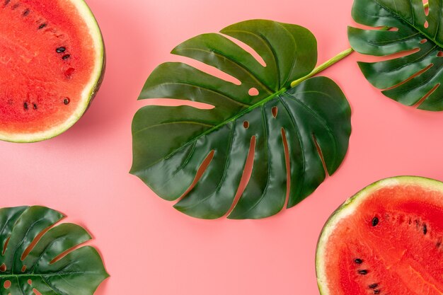 Wassermelone mit Palmenblättern lokalisiert auf rosa