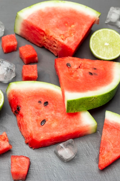 Wassermelone schneidet Kalkhälfte und Eis auf Grau