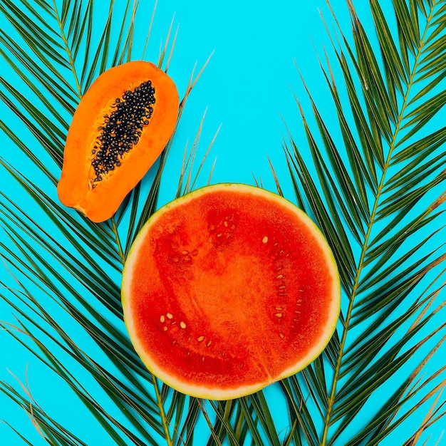 Wassermelone und Papaya auf blauem Hintergrund. Flache minimale vegane Kunst