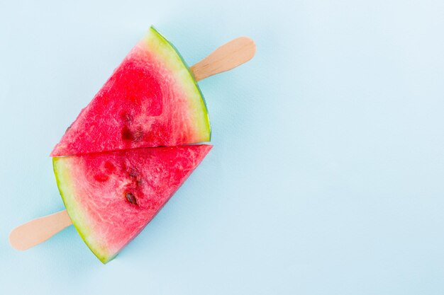 Wassermelonen-Popsicles auf einem türkisfarbenen Hintergrund Frische Wassermelonen auf Holzstäbchen