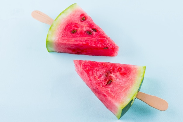 Wassermelonen-Popsicles auf einem türkisfarbenen Hintergrund Frische Wassermelonen auf Holzstäbchen