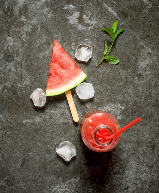 Wassermelonensaft mit Minze und Eis auf Steintisch.