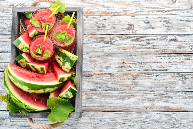 Wassermelonensaft mit Minze und Eis in einem Glas Melone auf weißem Holzhintergrund Freier Platz für Text Ansicht von oben