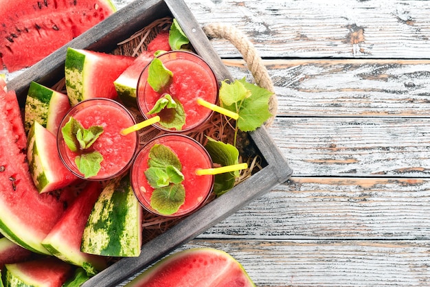 Wassermelonensaft mit Minze und Eis in einem Glas Melone auf weißem Holzhintergrund Freier Platz für Text Ansicht von oben