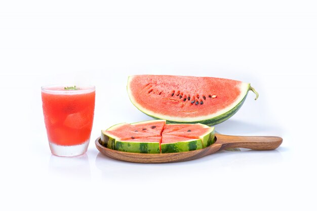 Wassermelonensaft mit Scheibenstück auf Holztablett und lokalisiert auf weißer Wand