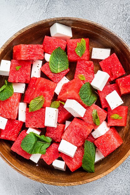 Wassermelonensalat mit feta-käse in einer holzplatte. weißer hintergrund. ansicht von oben.