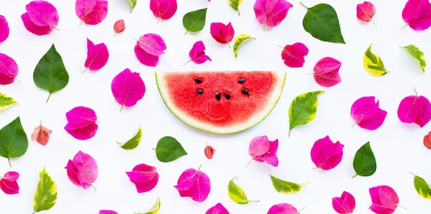 Wassermelonenscheibe mit schöner roter Bougainvilleablume und -blättern auf weißem Hintergrund. Sommer Hintergrundkonzept.