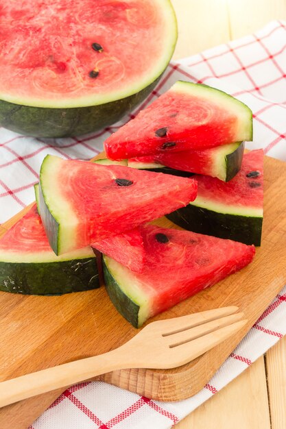 Wassermelonenscheiben auf hölzernem Brett, gedient mit Serviette auf einem hölzernen Hintergrund, oben geschlossen