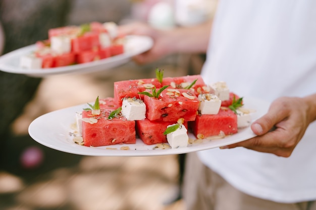 Wassermelonenscheiben mit Käse und Kräutern auf den Tellern