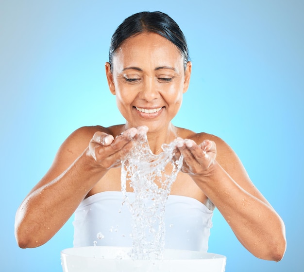 Wasserspritzer-Hautpflege und mit einer Frau, die ihr Gesicht für Schönheitsselbstpflege und Gesichtspflege auf blauem Hintergrund für Kosmetik- oder Dermatologie-Mockup wäscht Gesundheit Wellness und natürliche Modellreinigung Haut