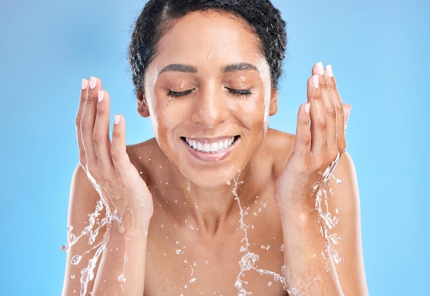 Wasserspritzer schwarze Frau Reinigung Gesicht auf blauem Hintergrund für Gesundheit Schönheit und Hautpflege Morgenroutine Hautpflege Luxuskosmetik und glückliche Frau mit Lächeln Make-up mit Wasser im Studio waschen