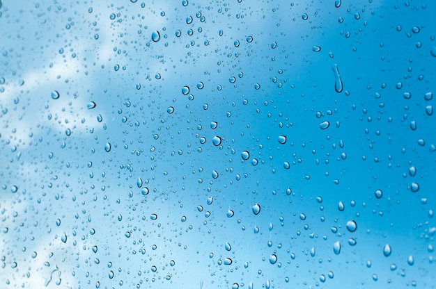 Foto wassertröpfchen auf fensterglas gegen blauen himmel, regenzeit