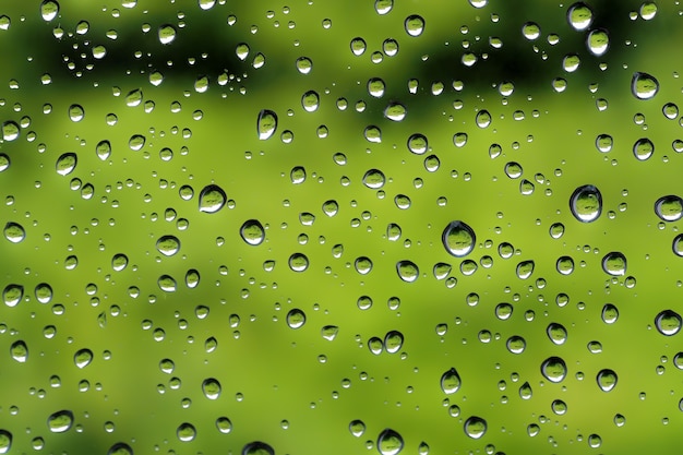 Wassertröpfchen nach Regen auf grünem Glas