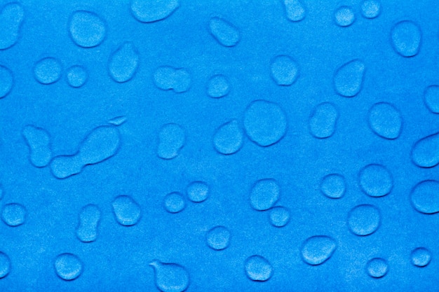 Wassertropfen auf einer blauen glatten Oberfläche.