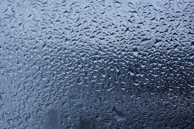 Wassertropfen auf einer dunkelblauen Glasoberfläche