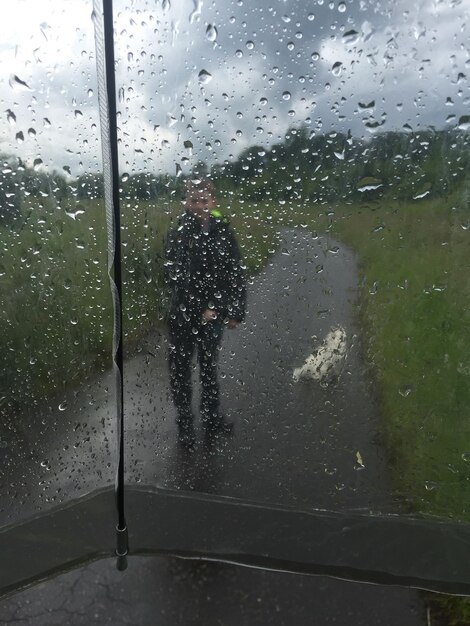 Foto wassertropfen auf glas gegen einen mann, der auf der straße geht