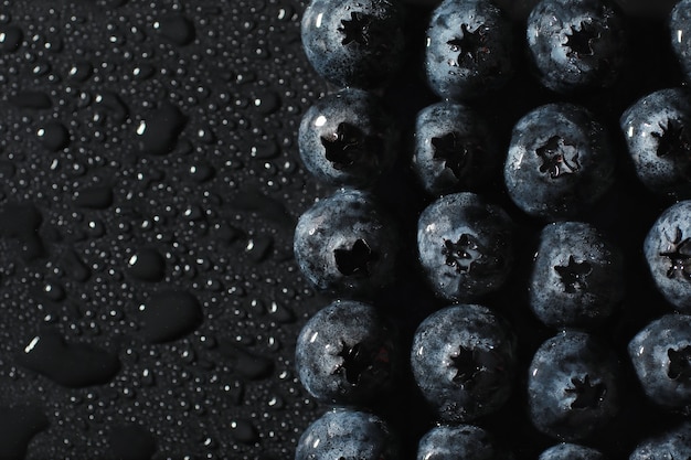 Wassertropfen auf reife süße Blaubeere. Frischer Blaubeerhintergrund mit Kopienraum für Ihren Text. Veganes und vegetarisches Konzept. Makrobeschaffenheit von Blaubeerbeeren. Textur Blaubeerbeeren hautnah