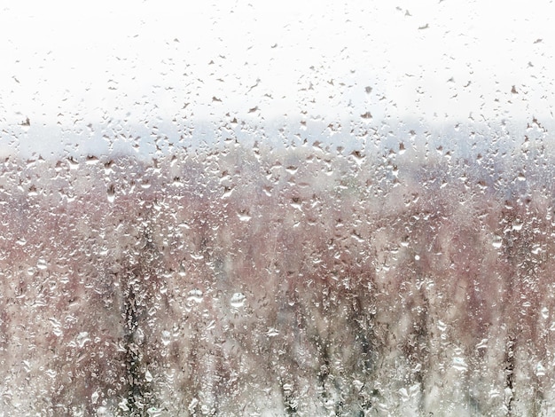 Wassertropfen aus schmelzendem Schnee auf der Fensterscheibe zu Hause