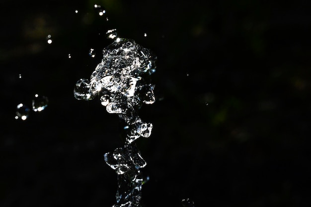 Foto wassertropfen schweben auf dunklem hintergrund. wasserspritzer im dunkeln mit umherfliegenden wassertropfen