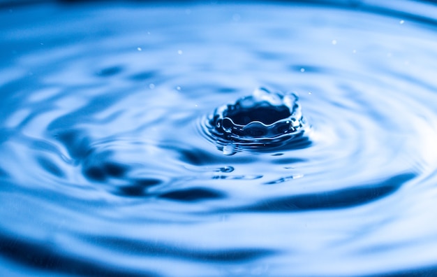 Wassertropfen spritzen in einem Glas blau gefärbt