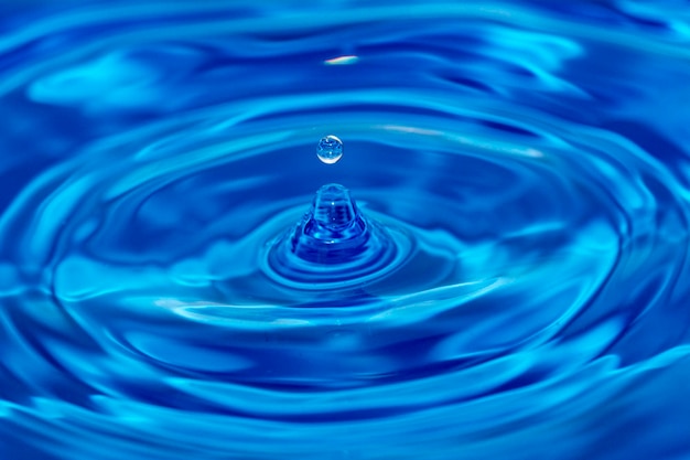 Wassertropfen spritzen in einem Glas blau gefärbt