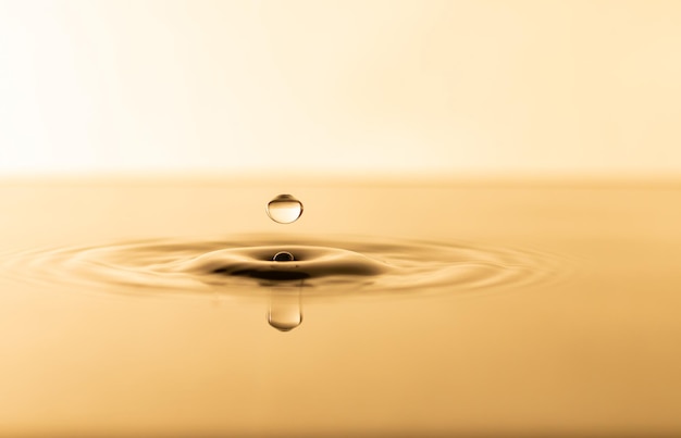 Wassertropfen Transparenter Wassertropfen mit kreisförmigen Wellen Leicht verschwommen goldgelb bespritzt Wassertröpfchen natürliches Wassertropfenkonzept und verwenden Sie es als Hintergrund