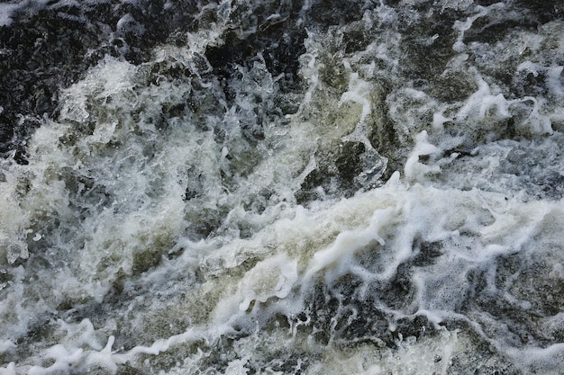 Wasserwellen des Flusses und des Meeres treffen sich bei Flut und Ebbe Tiefblaue stürmische Meerwasseroberfläche mit weißem Schaum und Wellenmuster Hintergrundfoto