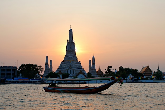 Wat Arun Ratchawararam Ratchawaramahawihan Templo do amanhecer com o barco de cauda longa ao pôr do sol