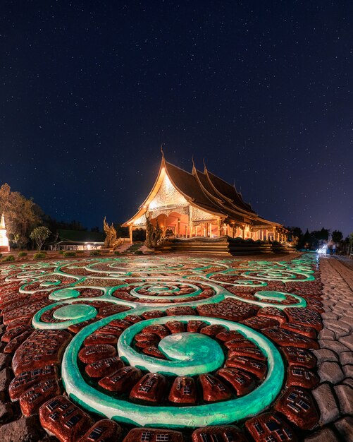 Wat Sirindhorn Wararam Tempel oder Wat Phu Prao mit beleuchteter Kirche und leuchtender Skulptur in der Nacht bei Ubon Ratchathani