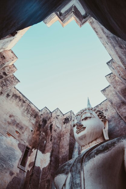 Wat tra phang thong lang enorme monumento de escultura de buda ao deus budista pregando com ofertas. escultura de pedra branca dentro da parede da mandapa. parque histórico de sukhothai.