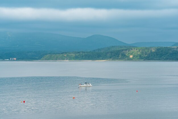 Waterscape de la bahía del mar con un barco de pesca y una costa montañosa de niebla en el fondo una vista del volcán Mendeleev desde el lado de la ciudad de YuzhnoKurilsk