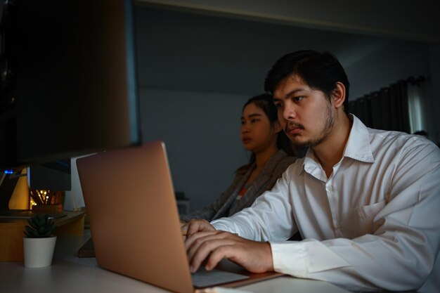 Web designers masculinos e femininos trabalhando em um novo projeto no escritório escuro