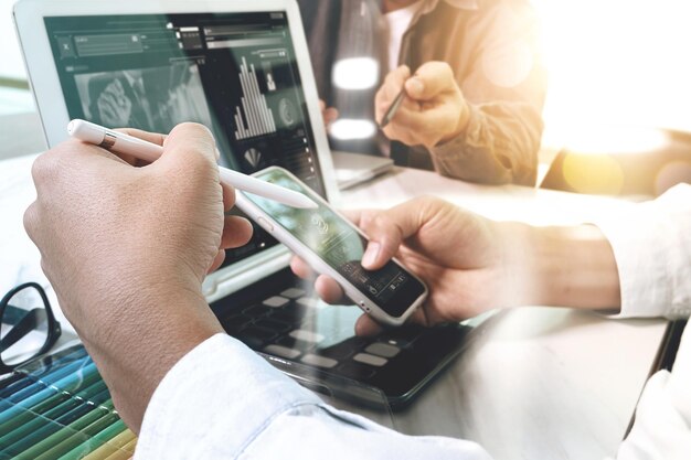 Webdesigner mit zwei Kollegen, der Daten und digitalen Tabletten- und Computerlaptop mit intelligentem Telefon bespricht