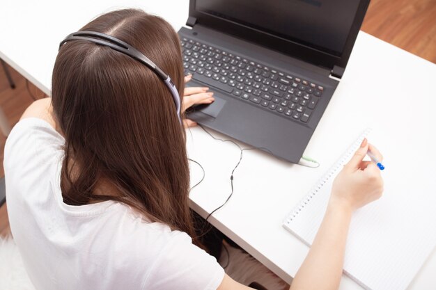 Webinar. Mädchen mit Kopfhörern mit Mikrofon vor einem Laptop