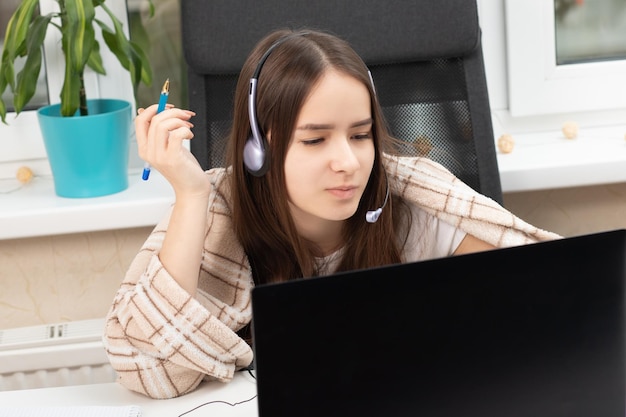 Webinar online Um aluno em casa está estudando com fones de ouvido com microfone tentando entender a palestra