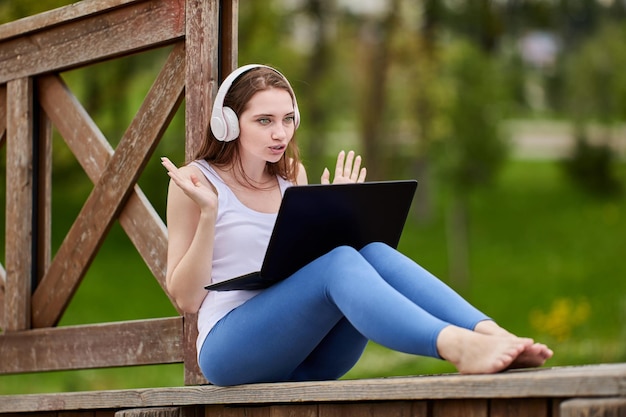 Webkonferenz über die Natur von Frau in schnurlosen Kopfhörern mit Laptop