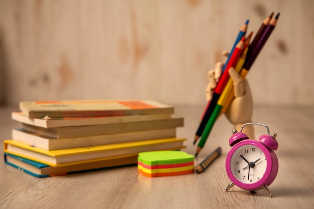 Wecker mit Büchern und artikulierter Holzhand zum Zeichnen mit Buntstiften und Posit