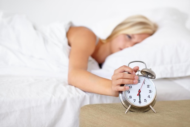Wecker und Frau aufwachen am Morgen auf dem Bett in der Heimat mit Müdigkeit und Ruhe Drücken Snooze und Mädchen frustriert mit der Zeit und müde starten den Tag im Schlafzimmer und Routine in der Wohnung mit Timer