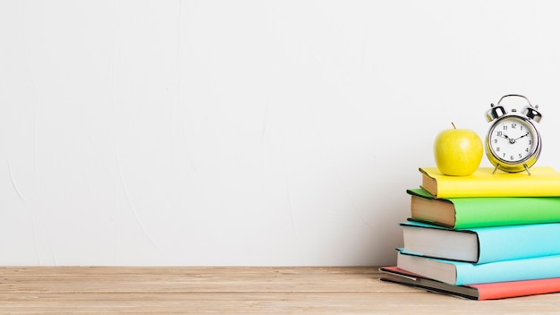 Foto wecker und gelber apfel auf stapel büchern