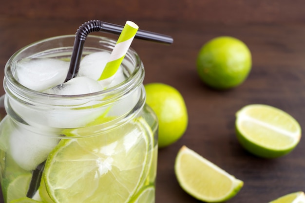 Weckglasglas Limonade mit Kalk und Stroh auf hölzernem Hintergrundbild