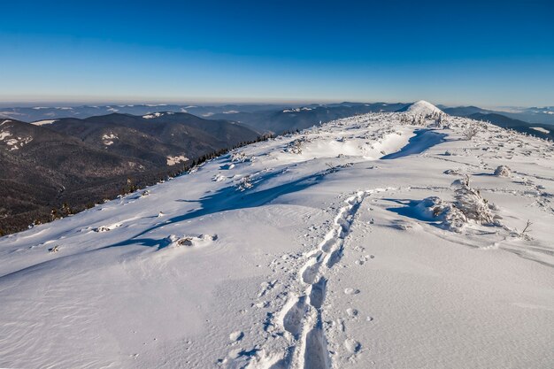 Weg mit Fußspuren im Schnee in den Winterbergen.