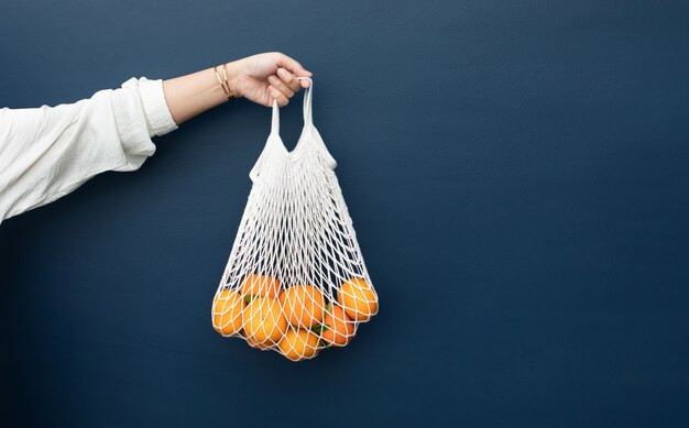 Weibchen mit frischer Orange aus dem Garten in Häkeltasche