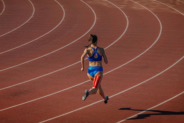 Weibliche Athletin läuft auf der Strecke mit Kinesio-Tape am Bein