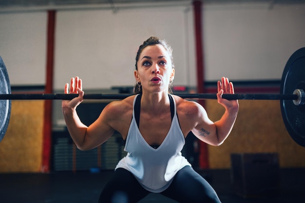 Weibliche Athletin trainiert mit einer Stange im Fitnessstudio