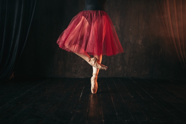 Weibliche Balletttänzer Beine in Punkten. Ballerina im roten Kleid und im schwarzen Tanz auf der Bühne im Theater
