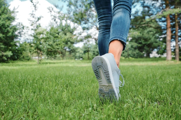 Weibliche Beine, die auf Gras gehen