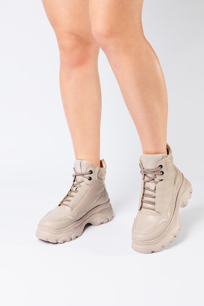 Weibliche Beine in beigen Lederschuhen aus der neuen Kollektion auf weißem Hintergrund Weibliche Beine in modischen Schuhen aus Ecoleather Frühjahr 2022