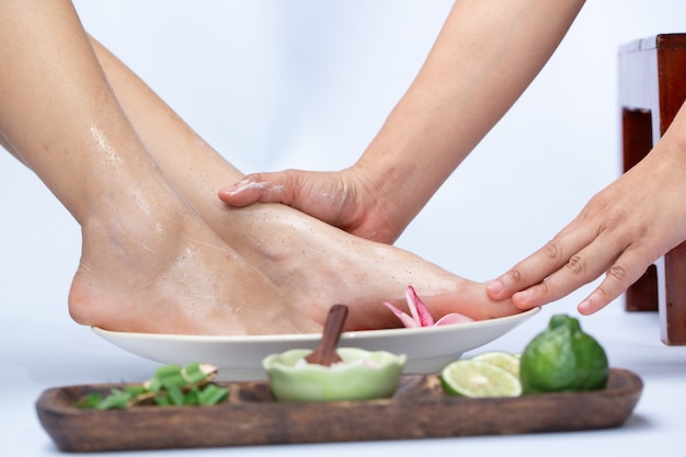 Weibliche Beine in der Wasserdekoration die Blumen Frau, die eine Pedikürebehandlung an einem Badekurort oder an einem Schönheitssalon mit dem Pediküristmassieren hat