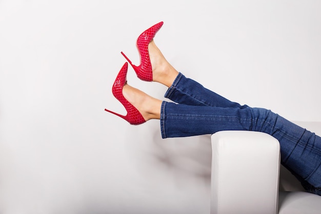 Weibliche Beine in Jeans und roten High Heels